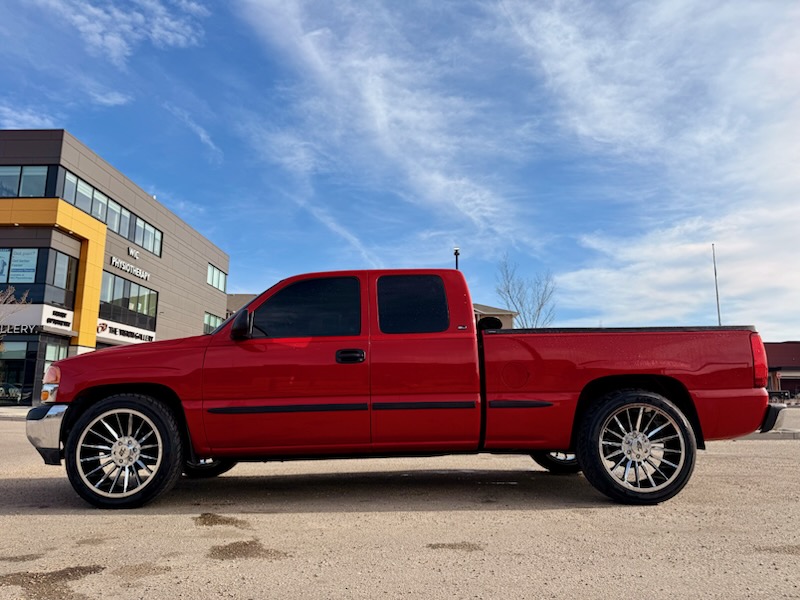 Red GMC Sierra extended cab on chrome multi-spoke wheels